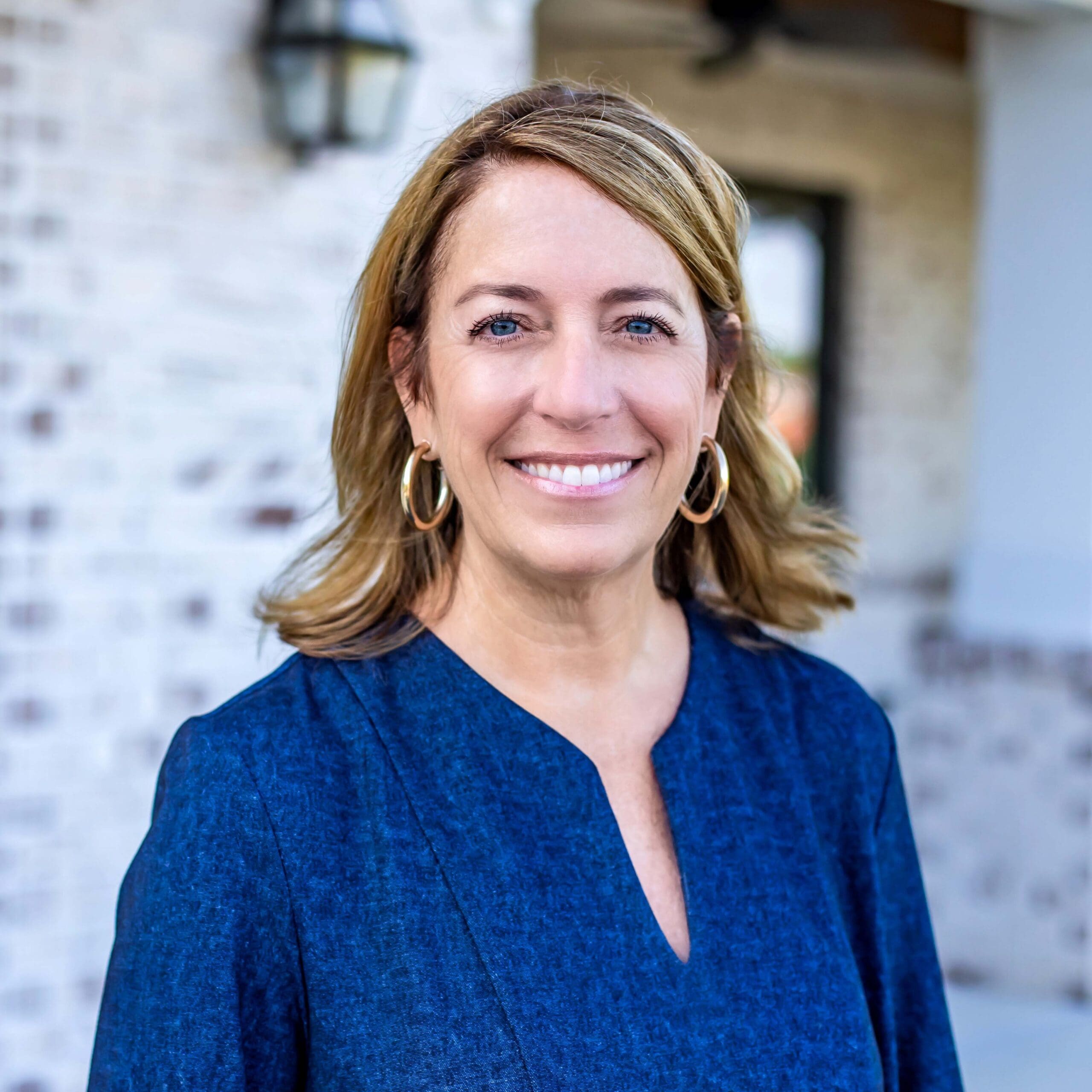 Dr. Monica M. Pierpan smiling and standing in front of a body of water while wearing a blue dress shirt
